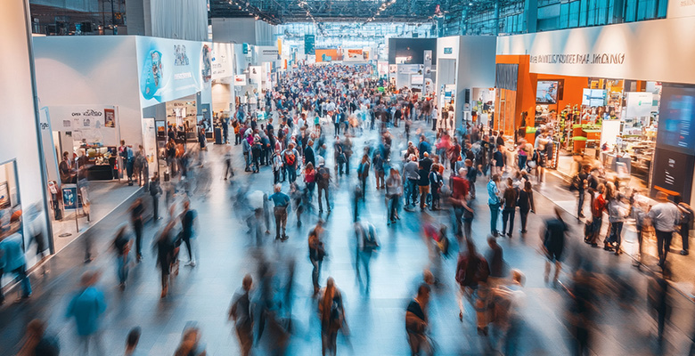 Blick von oben auf eine große, gut besuchte Messehalle mit zahlreichen Besuchern – Sinnbild für den weltweiten Einsatz auf jeder Messe.