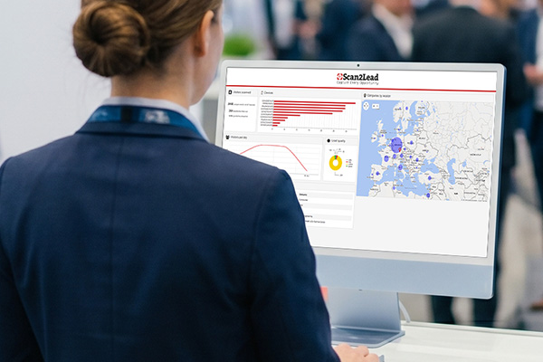 Standmitarbeiterin am Monitor mit dem Scan2Lead PORTAL (Diagramm und Karte) – Leads qualifizieren und auswerten.