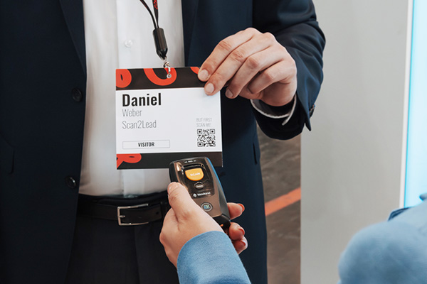 Mitarbeiterin scannt mit dem COLLECT-Miniscanner den Badge eines Besuchers – Badge-Scan direkt am Stand oder im Vorbeigehen.