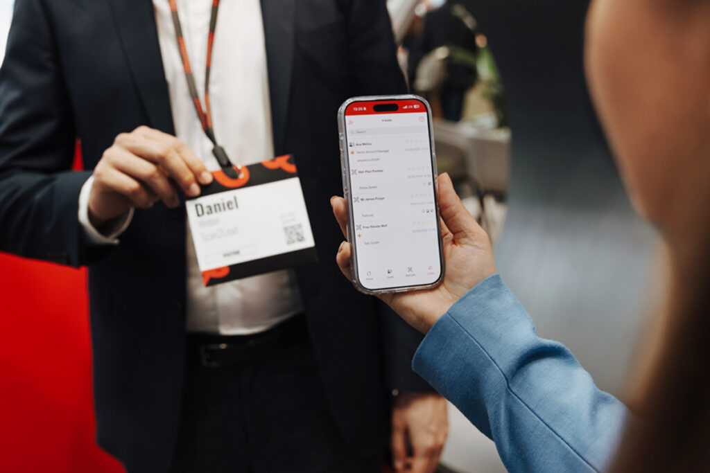 Person scannt den QR-Code auf einem Messebesucher-Badge mit der Scan2Lead App auf dem Smartphone.