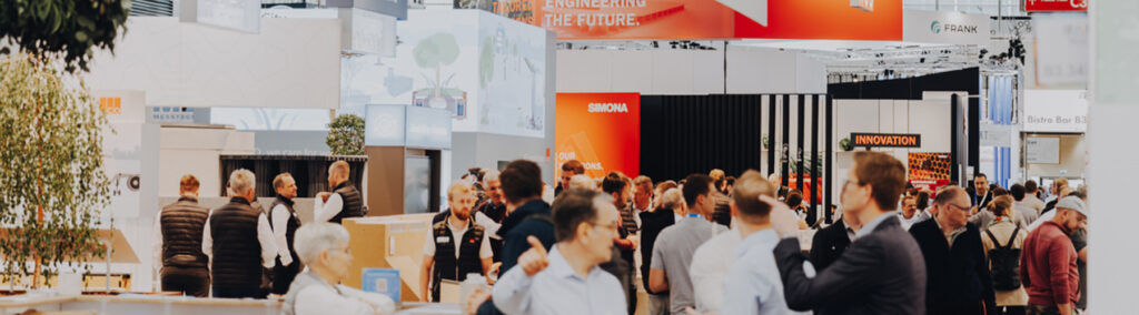 Gut besuchte Messehalle mit zahlreichen Fachbesuchern zwischen modernen Ausstellerständen.
