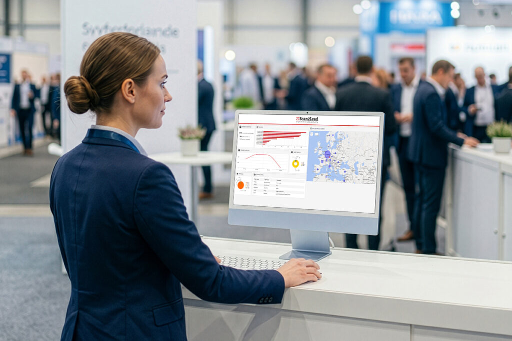 Standmitarbeiterin am Messestand betrachtet die Lead-Auswertung im Scan2Lead PORTAL auf einem Monitor.